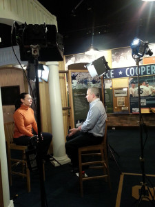 A man and woman are sitting in front of cameras.