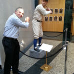 "I'll Knock a Homer for You" being screened at the Baseball Film Festival at National The Baseball Hall of Fame in Cooperstown, NY. Two men posing for a picture in front of a baseball display.