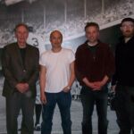 A group of men standing in front of a picture.