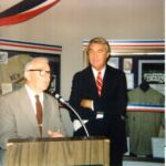 Two men in suits and ties are standing at a podium.