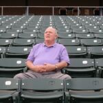 Shooting on location for "I'll Knock a Homer for You" A man sitting in the middle of an empty stadium.