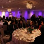 A group of people sitting at tables with plates and cups.