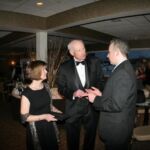 'I'll Knock a Homer for You' Producer/Director Andrew Lilley talking with actor James Rebhorn and his wife. A man and two women in suits talking to each other.