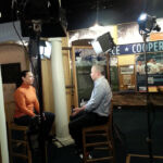 Producer/Director/Editor Andrew Lilley being interviewed by CBS News Correspondent Michelle Miller for CBS This Morning (Broadcast 2/6/2014) A man and woman are sitting in front of cameras.